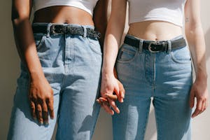 Close-up of interracial lesbian couple holding hands, expressing love and diversity in denim outfits.